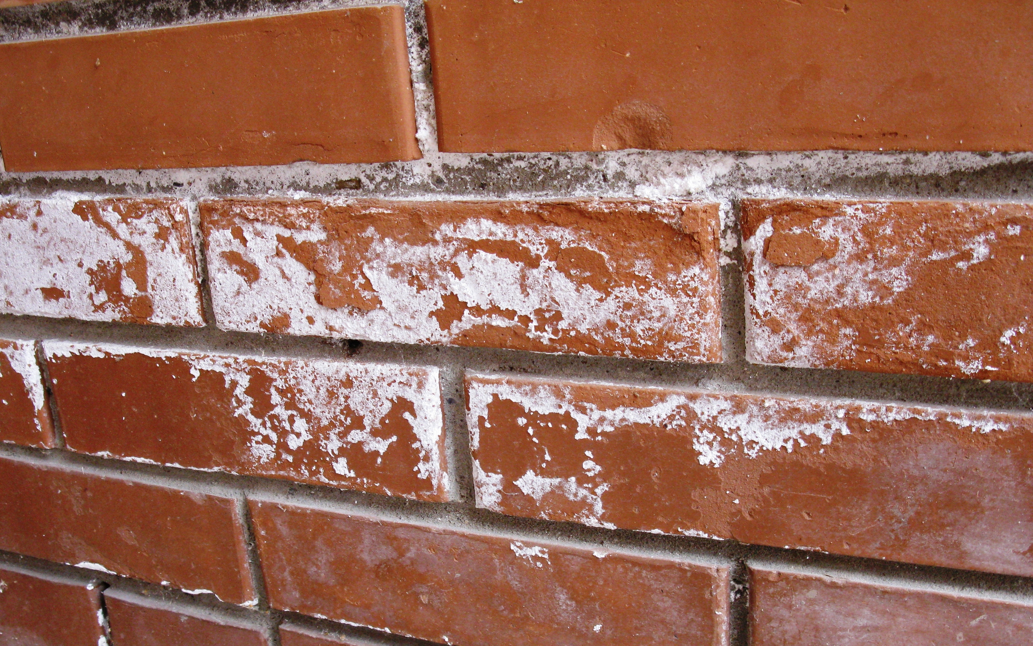 Результат солевой коррозии на фасаде: отшелушивание лицевого слоя, белесые пятна - высолы